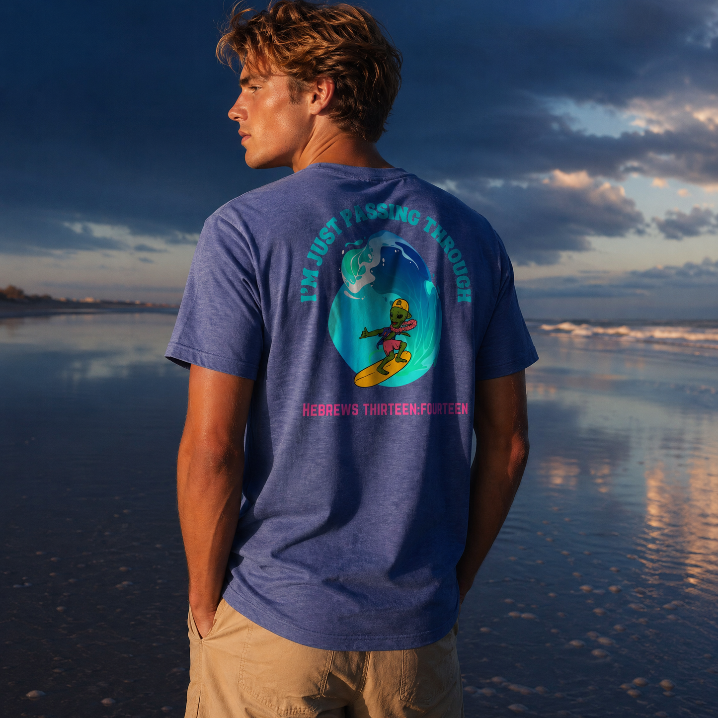 Person standing on a beach wearing a blue t-shirt with text I'm Just Passing Through