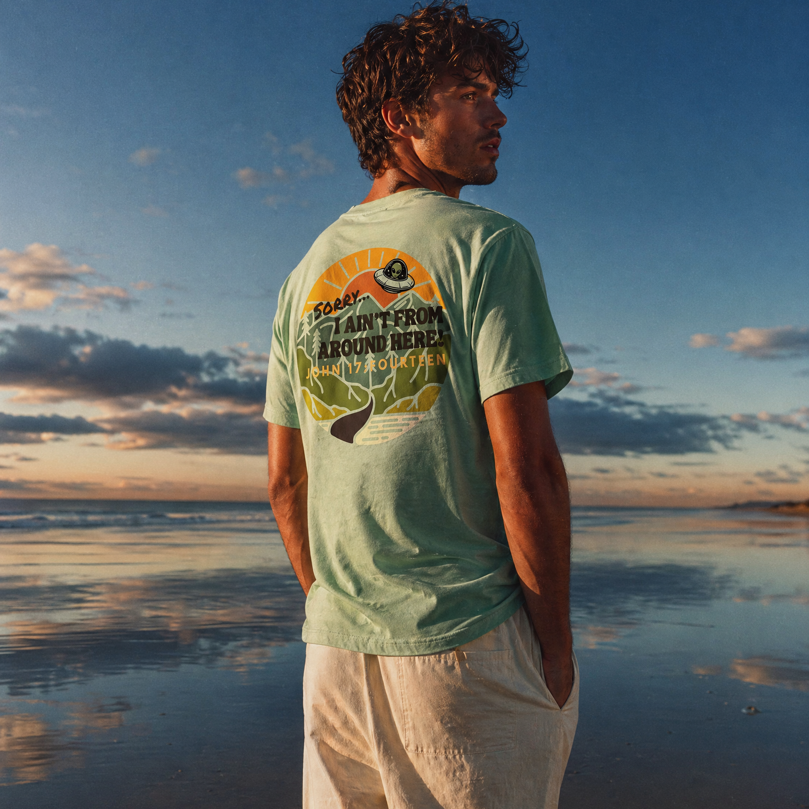 Person standing on a beach wearing a green t-shirt with text Sorry, I Ain't From Around Here