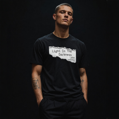 Man wearing a black Light In The Darkness t-shirt with text on a dark background