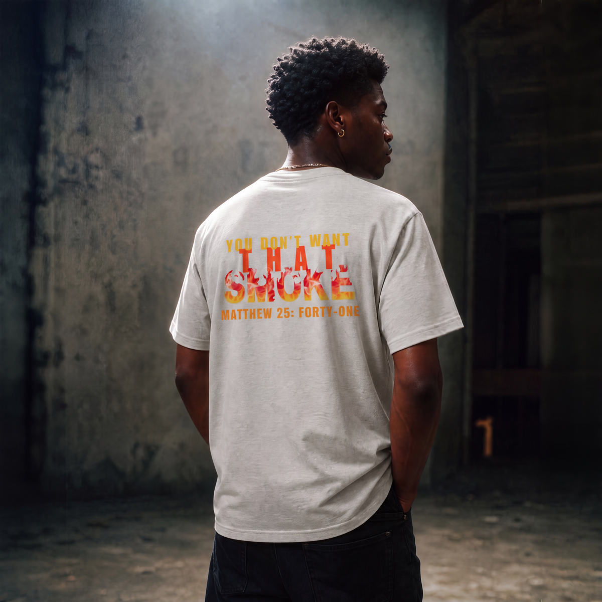 Model is wearing an ash gray t-shirt with a graphic print on the chest that reads 'YOU DON'T WANT THAT SMOKE MATTHEW 25:41' in yellow and orange flame-style lettering, posed against a gray studio background.