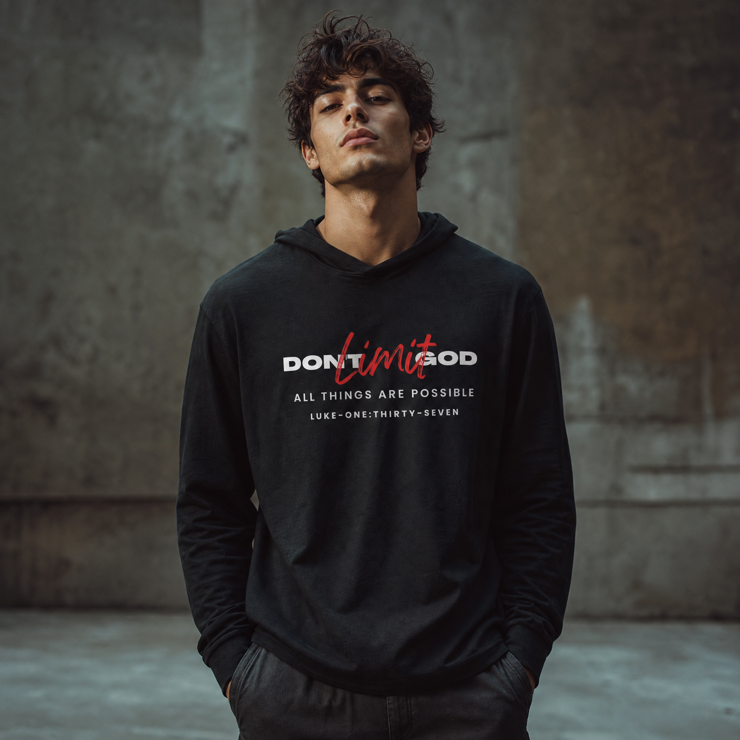 Person wearing a black hoodie with motivational text 'Don't Limit God' standing in front of a gray wall.