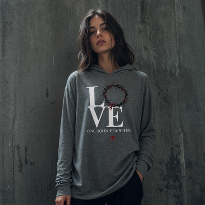 Model is wearing a gray long sleeve t-shirt hoodie with text 'LOVE' and a graphic of the crown of thorns in place of the 'O' standing in front of a gray wall.