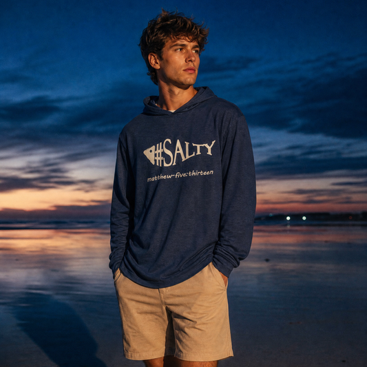 Person wearing a hoodie with '#SALTY'  on a beach at sunset.