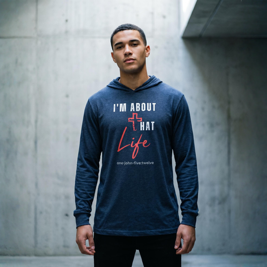 Man wearing a blue hoodie t-shirt with text 'I'm About That Life' standing near a concrete wall.