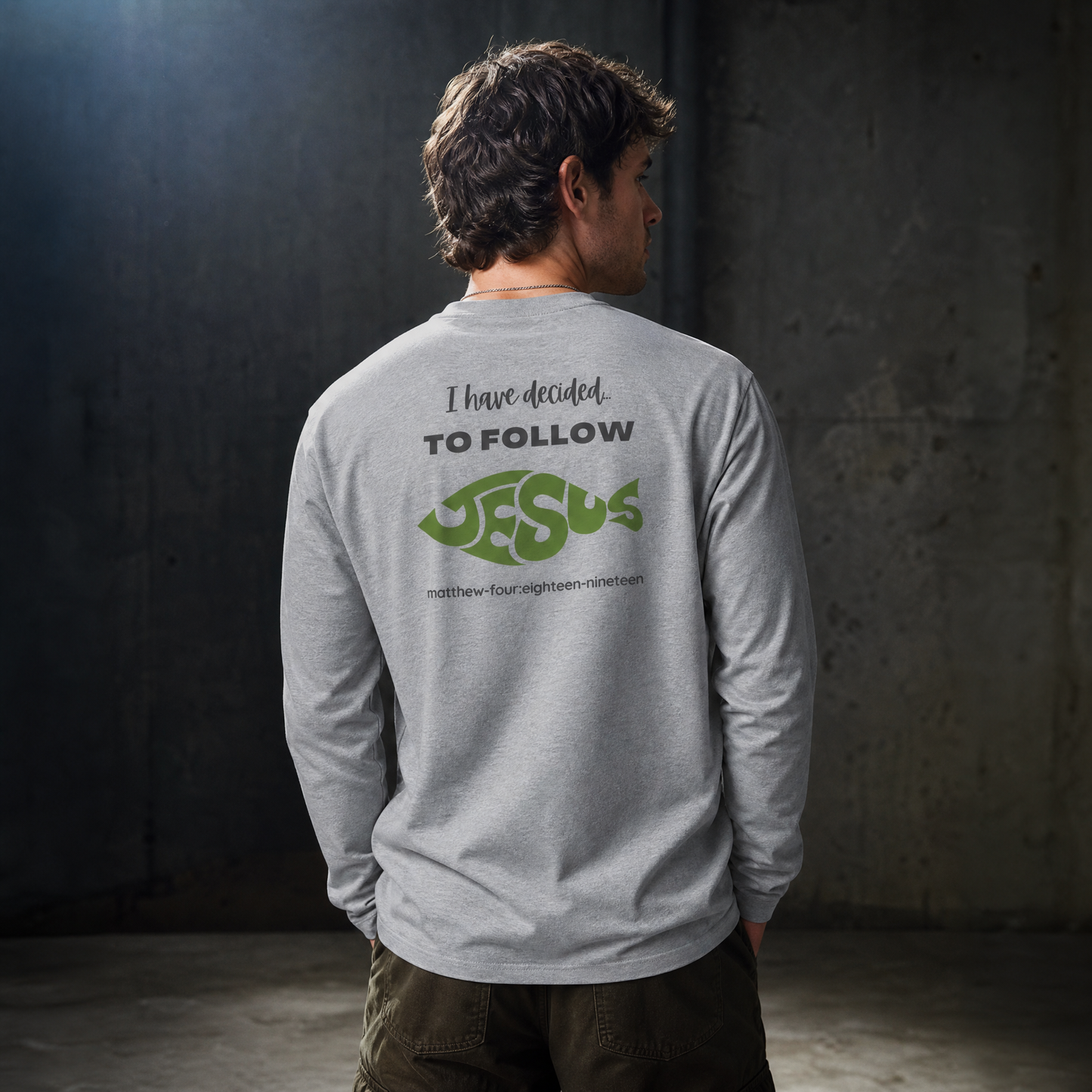 Person wearing a gray long sleeve t-shirt with text 'I Have Decided To Follow Jesus' standing near a gray wall.