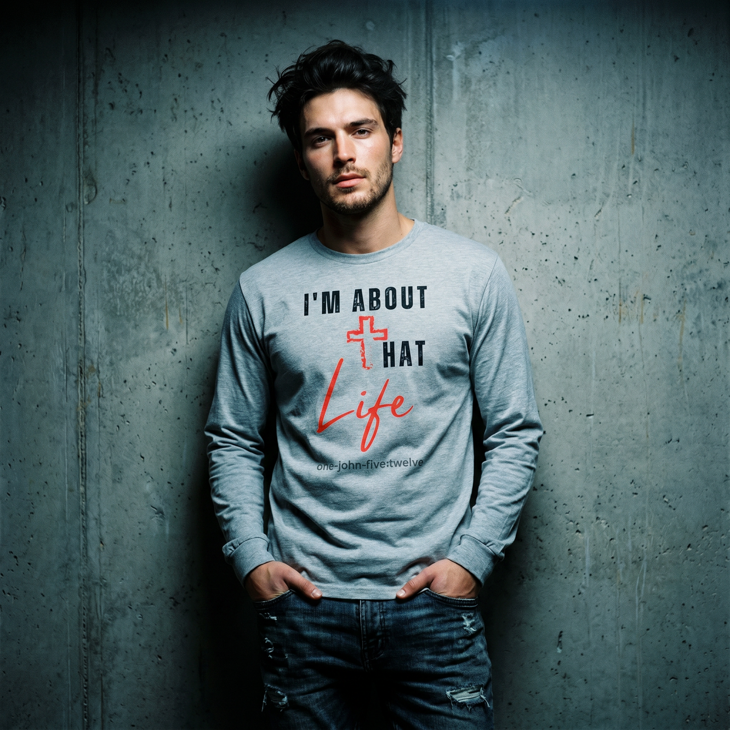 Man wearing a gray long-sleeve shirt with text 'I'm About That Life' standing against a textured gray wall