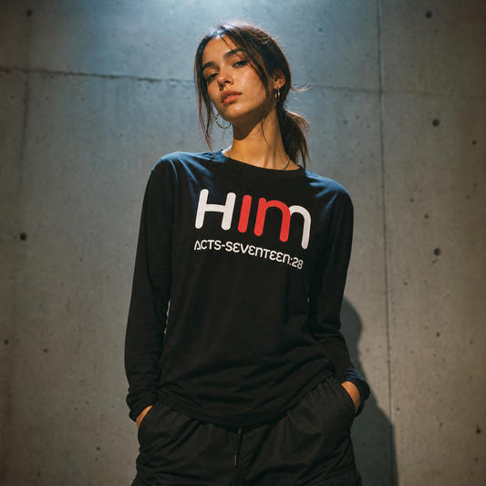 Person wearing a black long-sleeve t-shirt with 'IN HIM' text against a concrete wall.