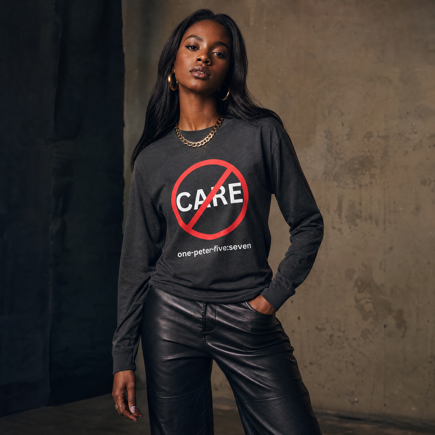 Person wearing a dark gray long-sleeve t-shirt with a "Don't Care" logo against a  gray textured wall.