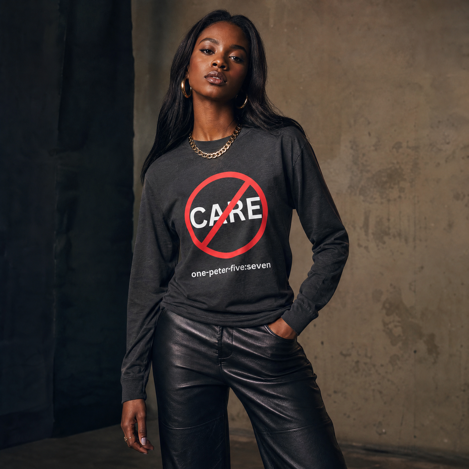 Person wearing a dark gray long-sleeve t-shirt with a "Don't Care" logo against a  gray textured wall.