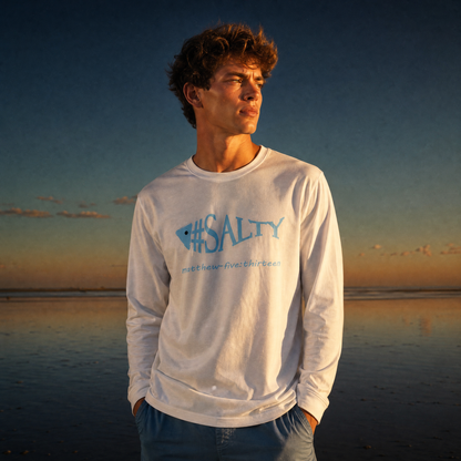 Man wearing a white '#SALTY' t-shirt on a beach at sunset