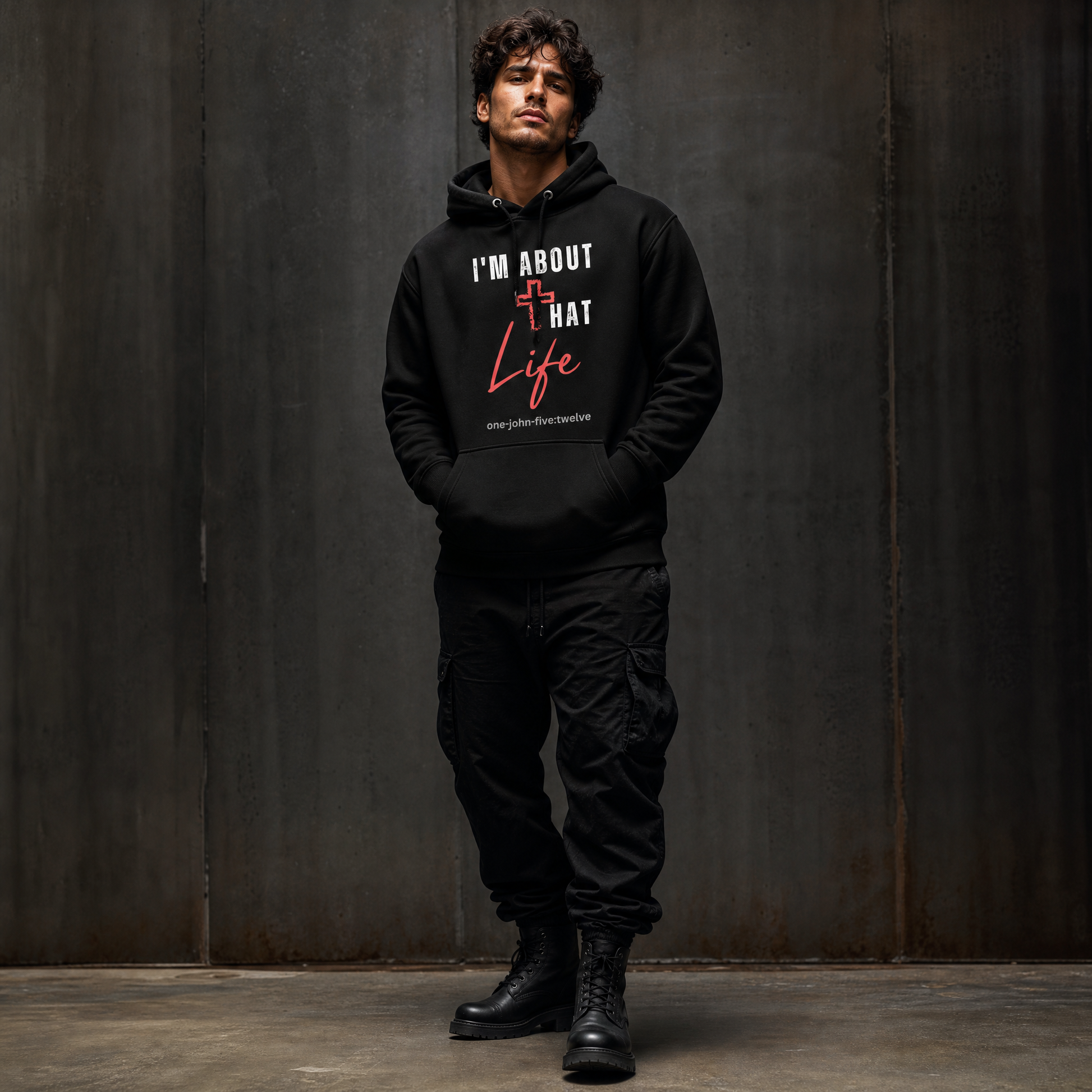 Person wearing a black 'I'm About That Life' hoodie sweatshirt, standing next to a dark wall.