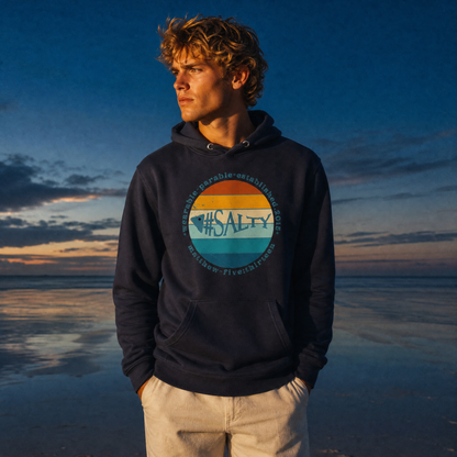 Person wearing a hoodie with a '#Salty' standing on a beach at sunset