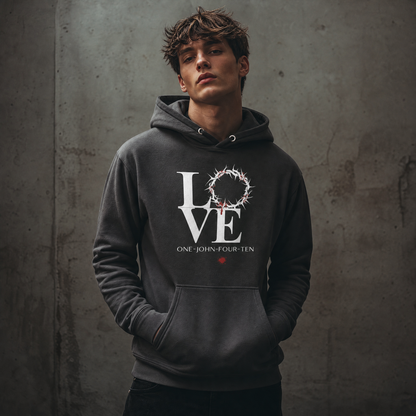 Model is wearing a vintage black hoodie with text 'LOVE' and a graphic of the crown of thorns in place of the 'O' standing against a gray wall.