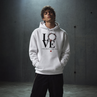 Model is wearing a white hoodie with text 'LOVE' and a graphic of the crown of thorns in place of the 'O' standing against a gray wall.