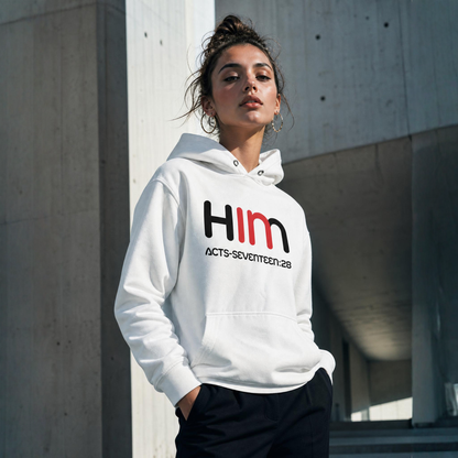 Person wearing a white hoodie with 'IN HIM' logo standing near a concrete wall.