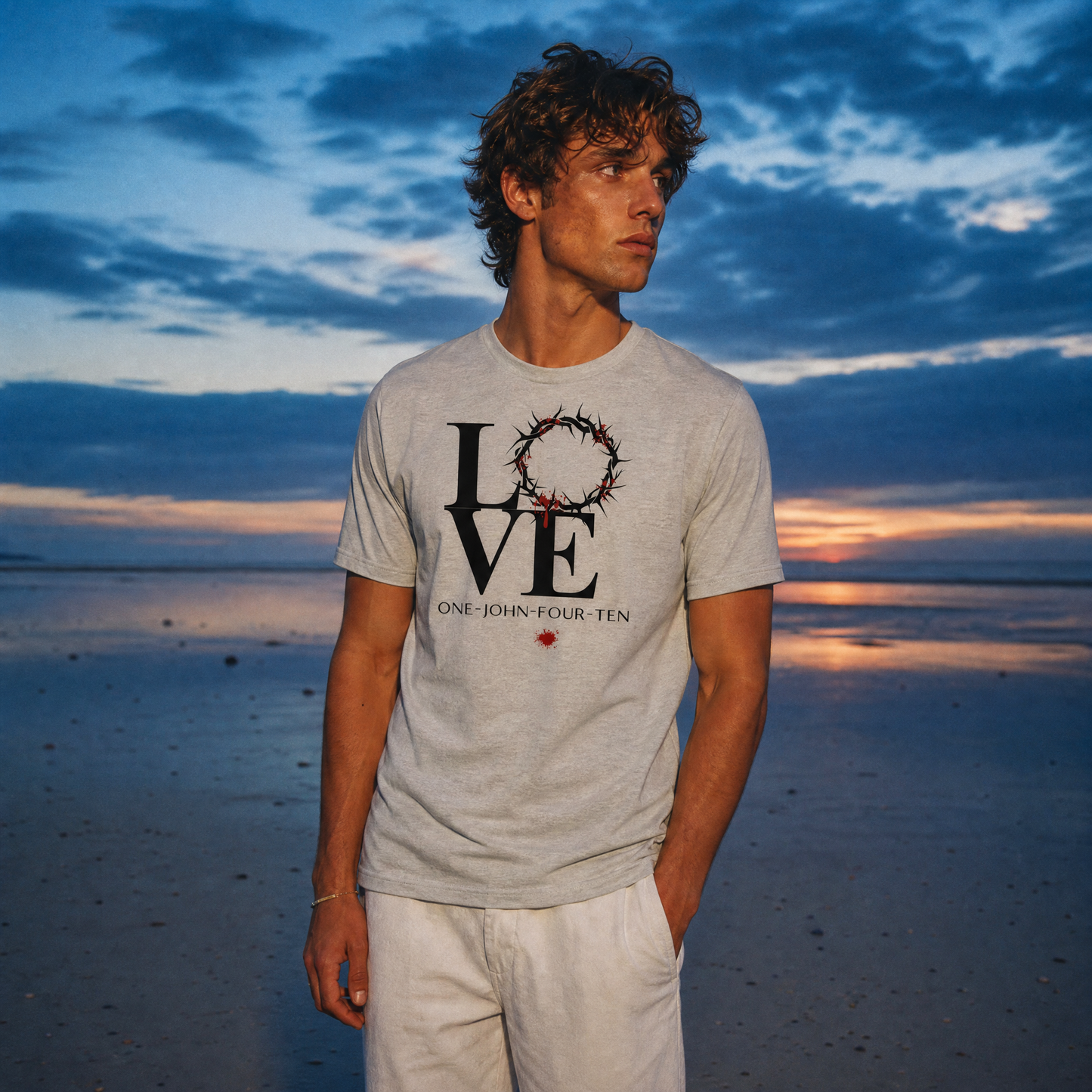 Model is wearing a gray t-shirt with text 'LOVE' and a graphic of the crown of thorns in place of the 'O' standing on the beach.