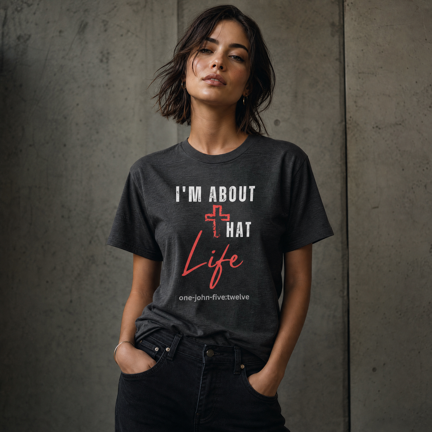 Person wearing a dark gray 'I'm About That Life' t-shirt standing next to a gray wall.