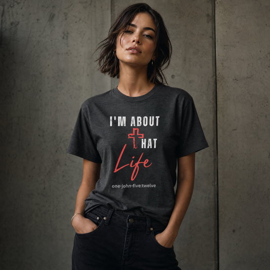 Person wearing a dark gray 'I'm About That Life' t-shirt standing next to a gray wall.