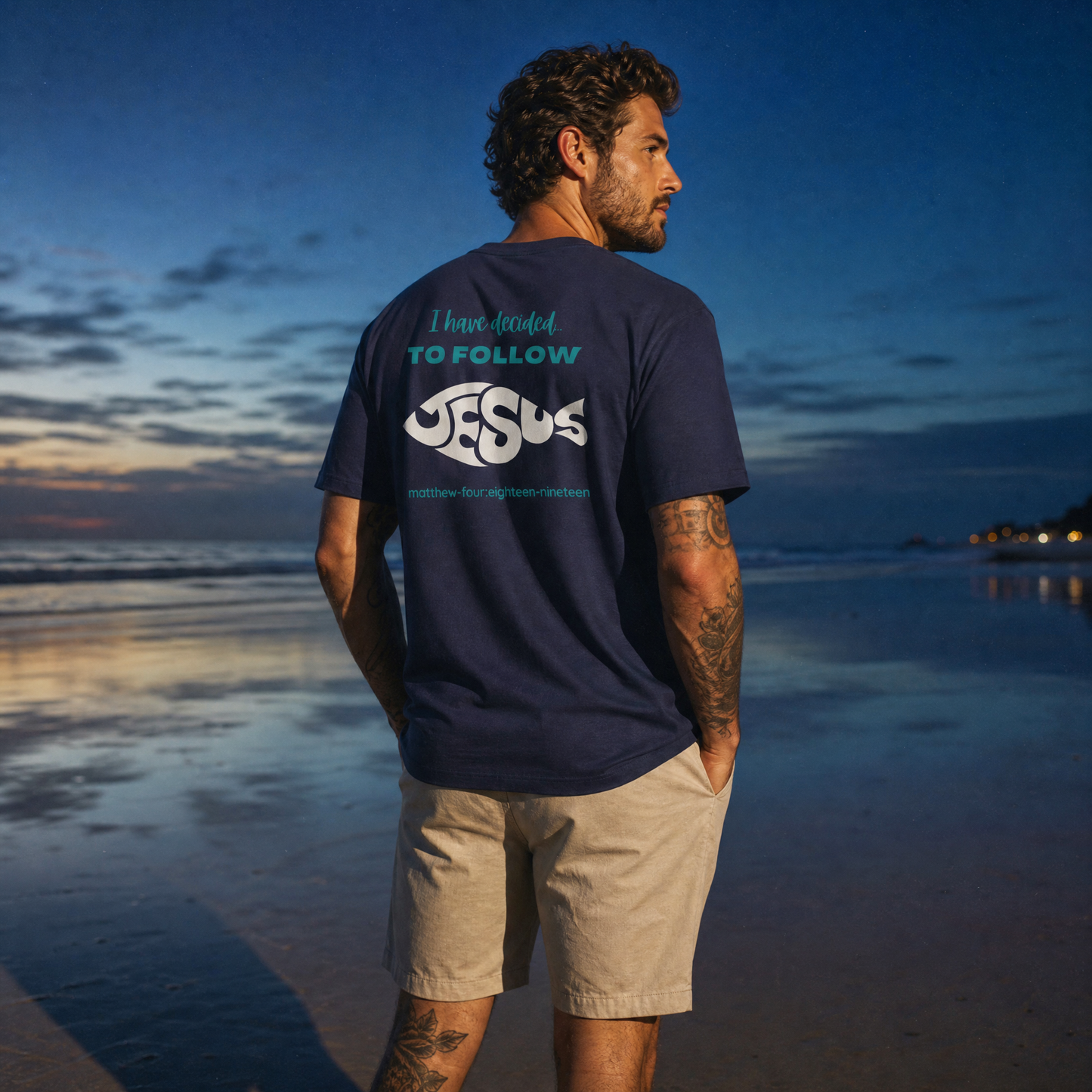 Person wearing a navy blue t-shirt with 'I have decided to follow Jesus' text on the beach at sunset.