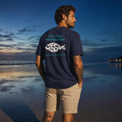Person wearing a navy blue t-shirt with 'I have decided to follow Jesus' text on the beach at sunset.