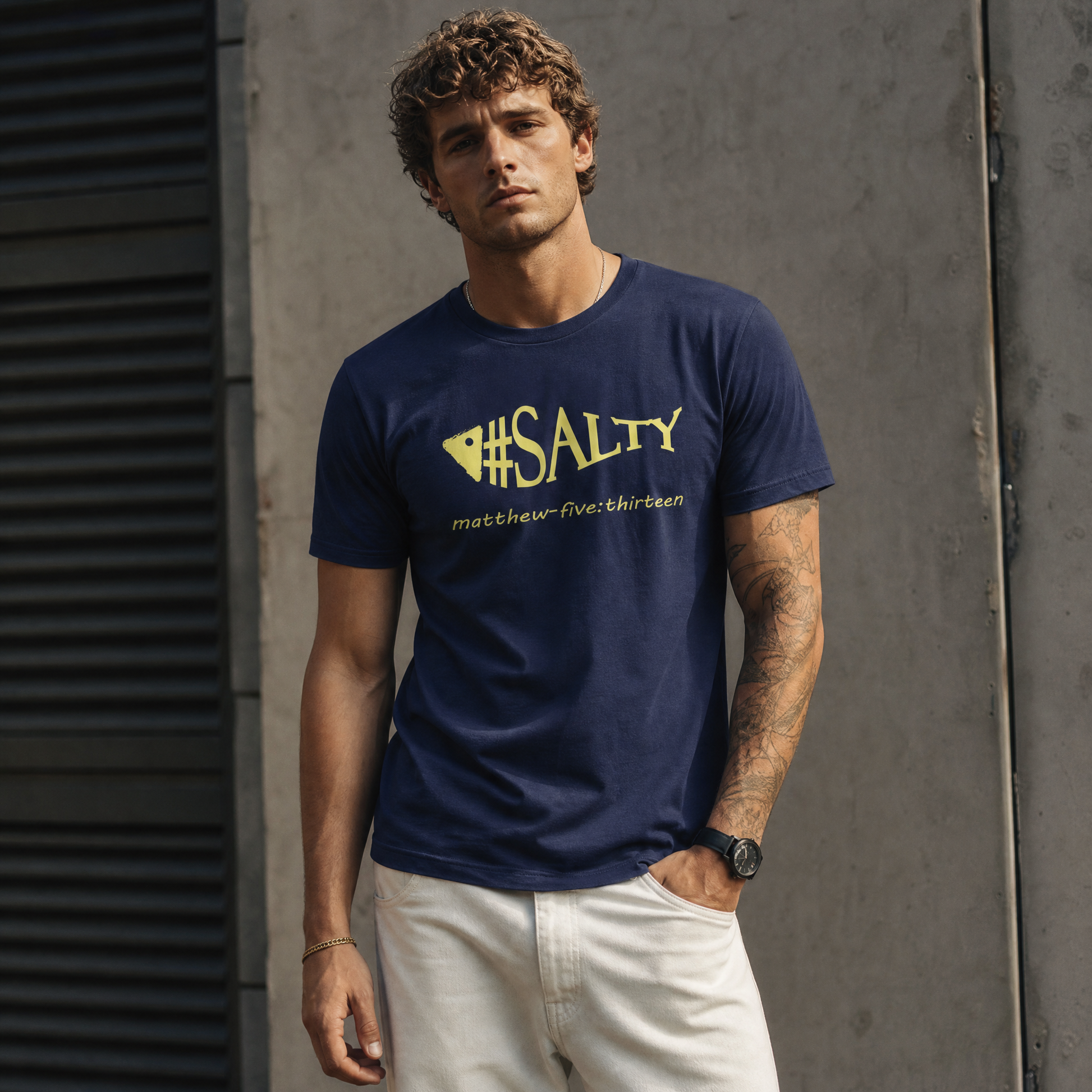 Person wearing a navy blue t-shirt with text  "#SALTY" standing in front of a concrete wall