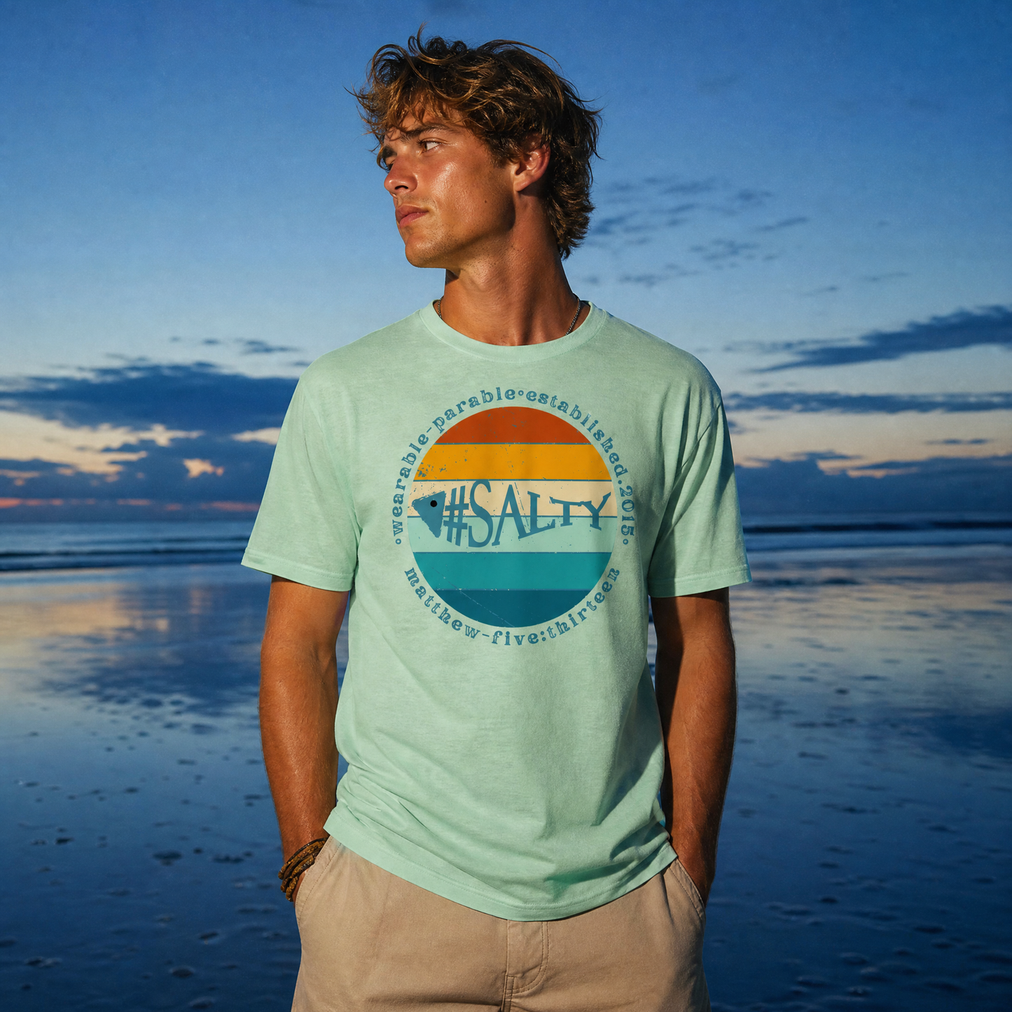 Man wearing a '#SALTY' t-shirt against a sunset beach backdrop