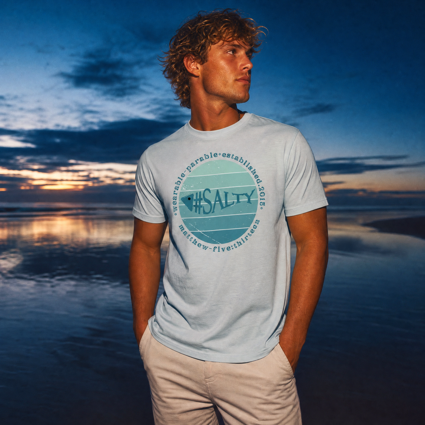 Person wearing a '#SALTY' t-shirt on a beach at sunset