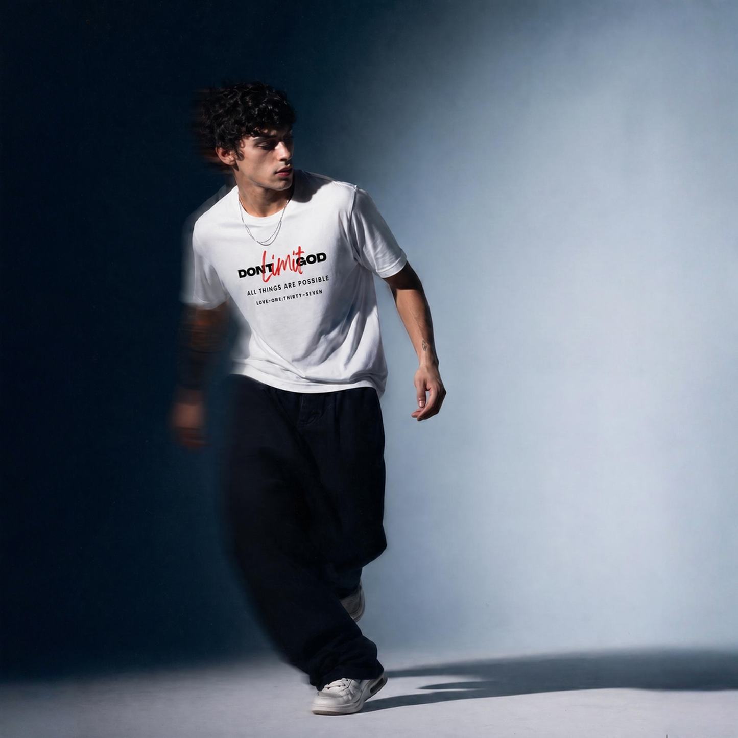 Person wearing a white t-shirt with text 'Don't Limit God' and dark pants against a gradient background