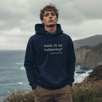 Man wearing a navy hoodie with text Suck It Up Buttercup standing by a coastal landscape
