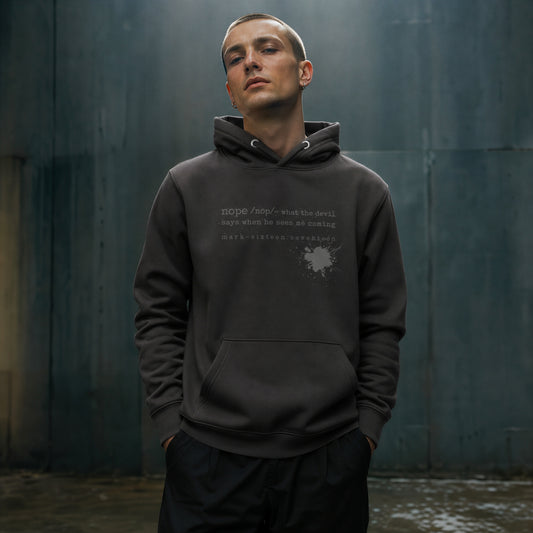 Man wearing a dark hoodie with text against a textured wall.